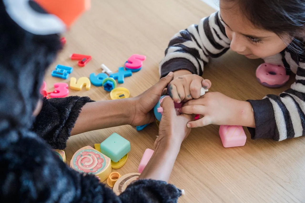 An adult helping a child with a hands-on classroom activity